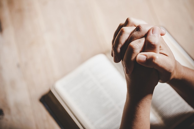 Hands praying over an open bible