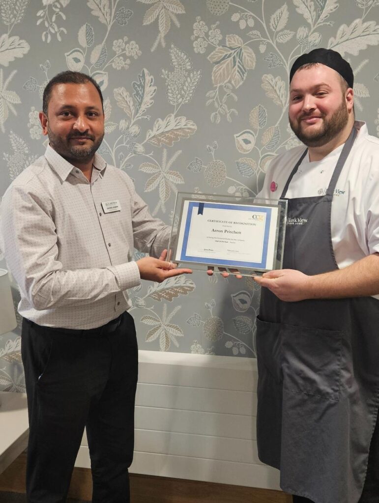 our home manager presenting a certificate and badge to our head chef