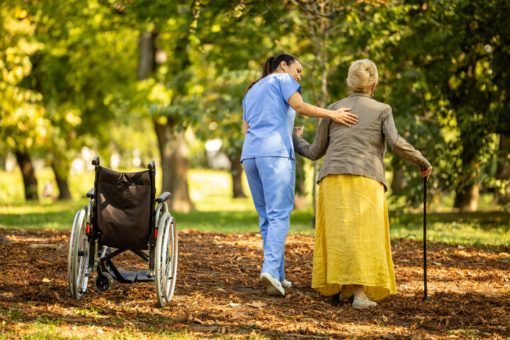 carer and resident in the garden helping her walk